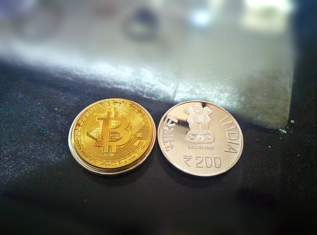 two gold-colored Bitcoin and 20 Indian rupee coin